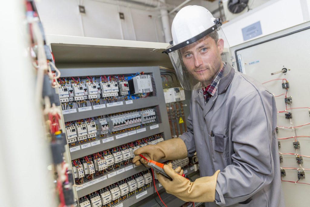 eletricista efetuando manutenção em um painel de elétrica industrial